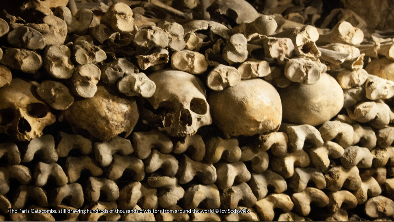 Skulls and long bones piled up against the walls of the Paris catacombs