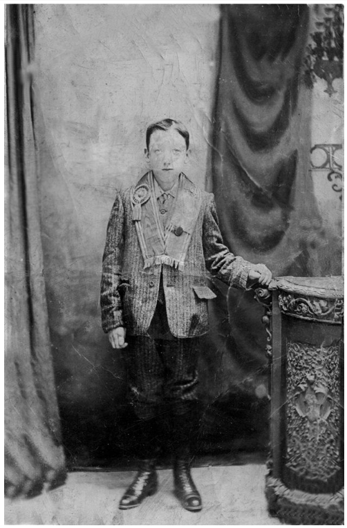 Black and white photo of a boy with an orange sash